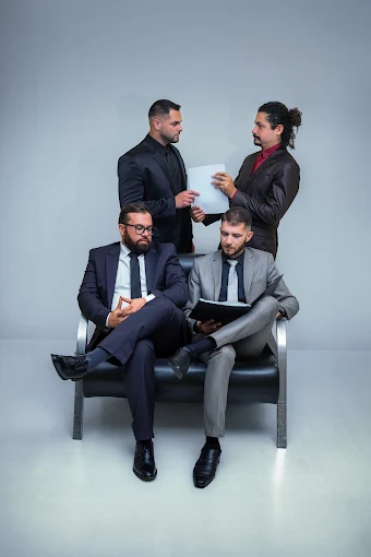 Equipe do escritório: dois advogados sentados e dois em pé, com documentos em mãos.